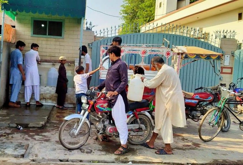 Families filling water containers at the free Salma Khatoon Foundation clean water plant in Sahiwal