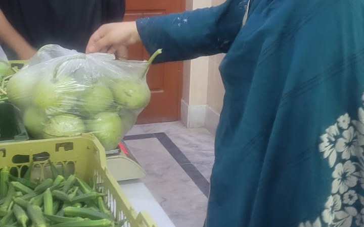 A woman selling okra and round gourds grown on the Salma Khatoon Foundation farm